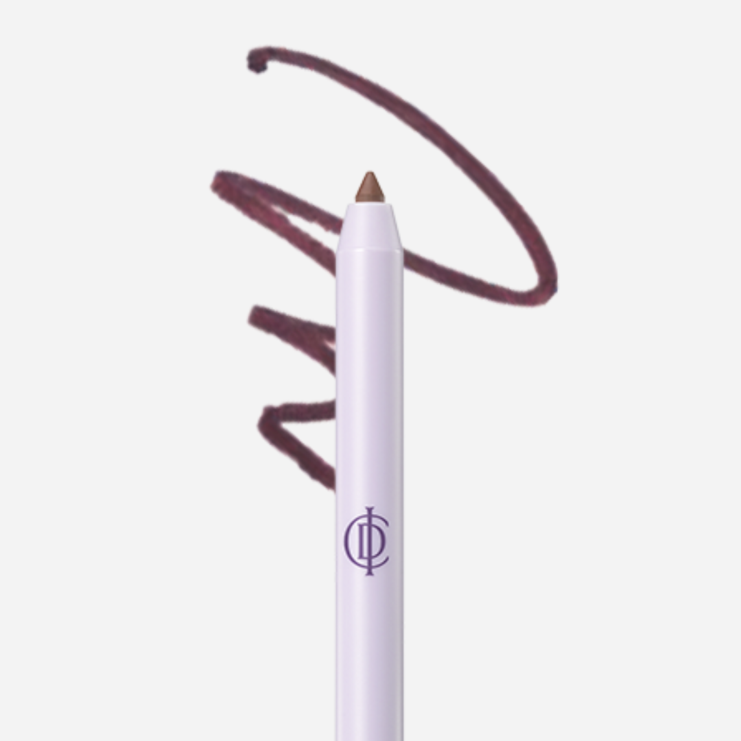 A lip liner pencil with a white barrel and a pointed brown tip, shown against a light gray background with a dark mauve-brown swatch of product written above it. A stylized purple monogram logo is visible on the barrel.
