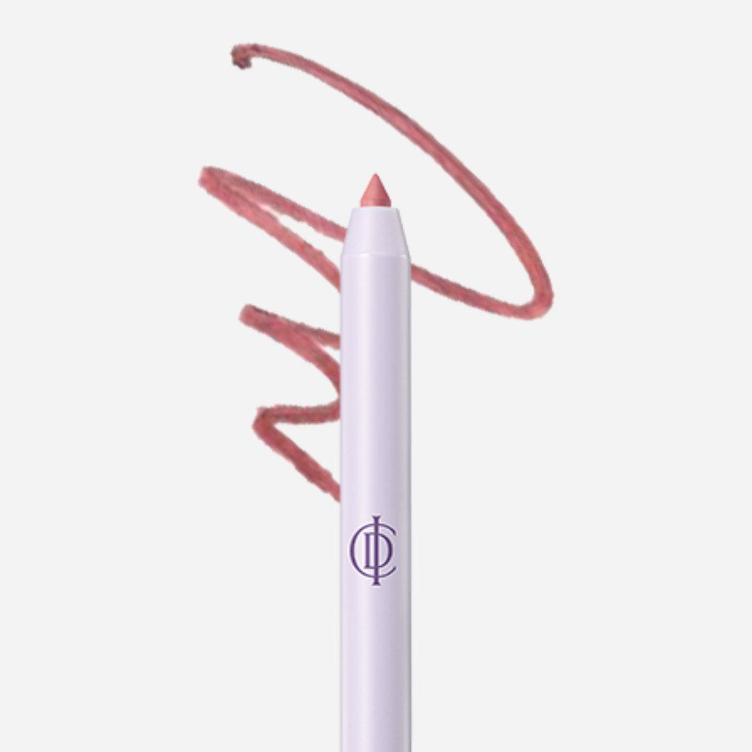 A lip liner pencil with a pale lavender-white barrel and a peachy pink tip, shown against a light gray background with a matching pink swatch scribble behind it. A stylized purple monogram logo is printed on the barrel.